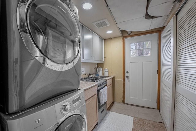 laundry area with laundry area, visible vents, a sink, and stacked washing maching and dryer