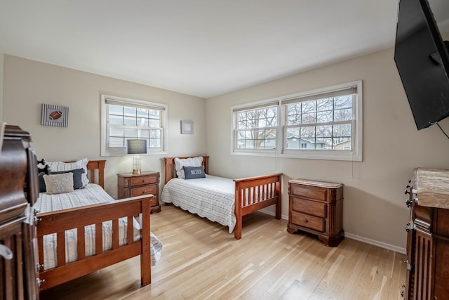 bedroom with multiple windows, light wood-style flooring, and baseboards