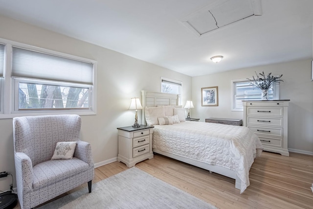 bedroom with attic access, light wood-style flooring, and baseboards