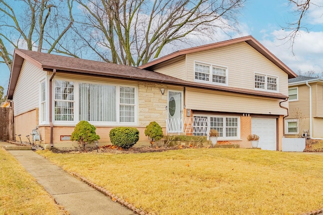 tri-level home with an attached garage, brick siding, and a front yard