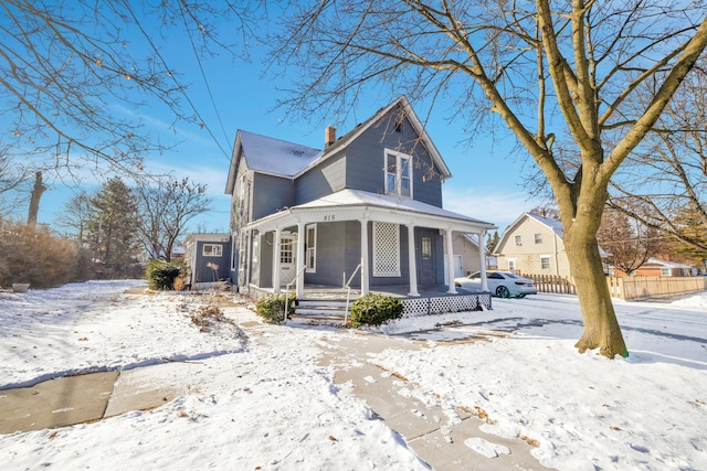 victorian home featuring a porch, fence, and a chimney