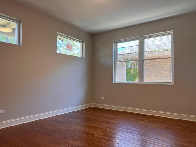 unfurnished room with dark wood finished floors, visible vents, and baseboards