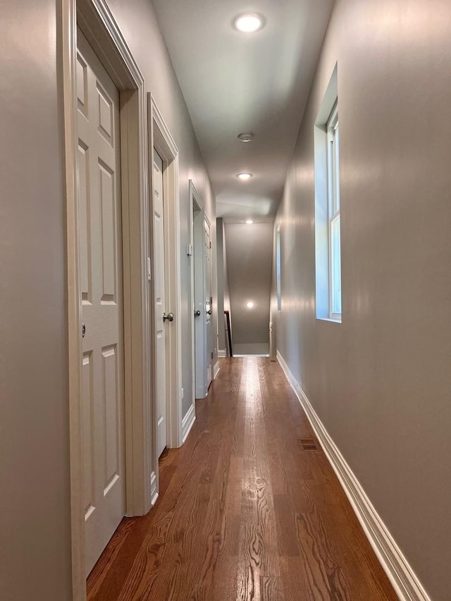 hall with baseboards and dark wood-type flooring