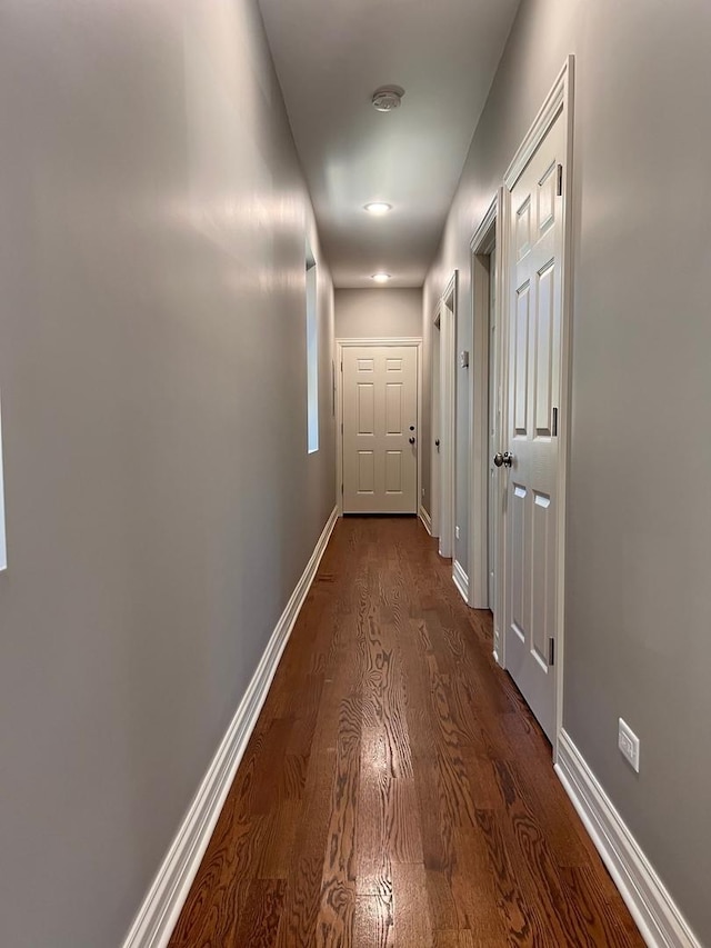 corridor with dark wood-type flooring and baseboards