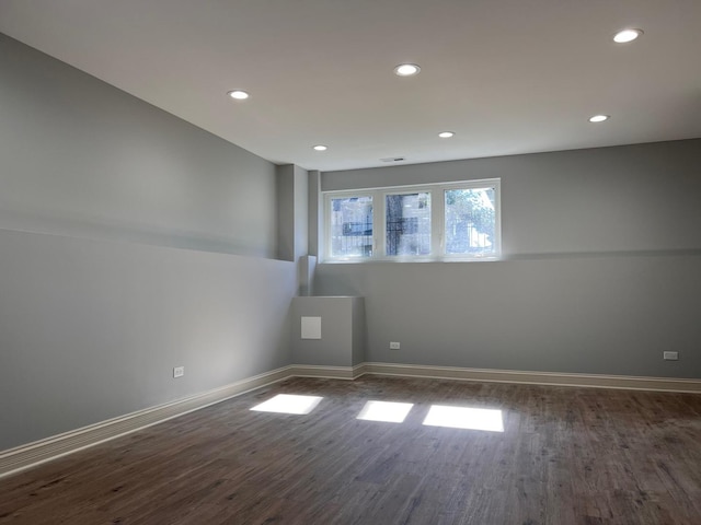 spare room with dark wood-type flooring, recessed lighting, and baseboards