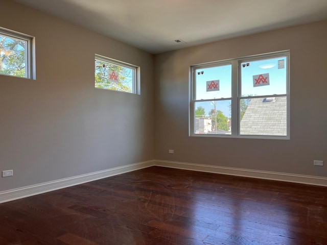 spare room featuring dark wood-style floors and baseboards