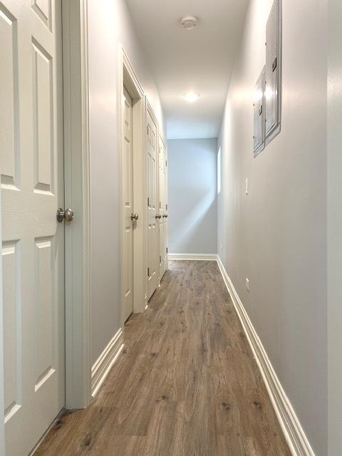 corridor with baseboards and wood finished floors