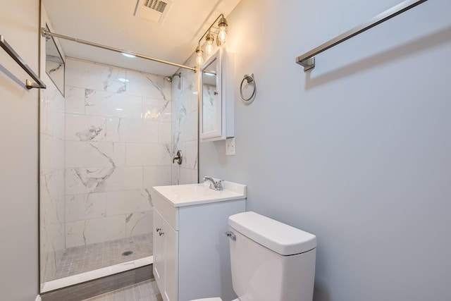 bathroom featuring toilet, visible vents, a tile shower, and vanity