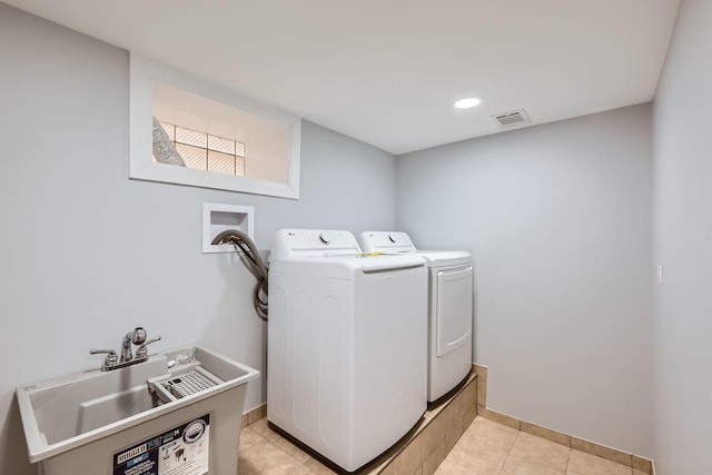 washroom featuring laundry area, baseboards, visible vents, washing machine and clothes dryer, and a sink