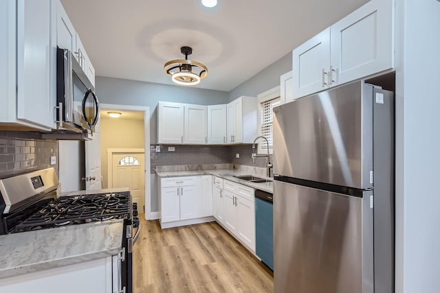 kitchen featuring white cabinets, light wood-type flooring, stainless steel appliances, and a sink