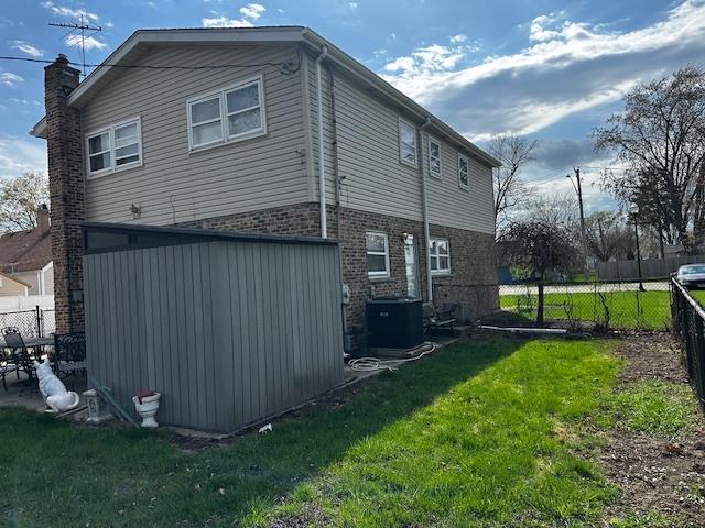 115 N Lavergne Ave, Northlake, IL 60164 - back of house with cooling unit, a shed, brick siding, an outdoor structure, and a chimney