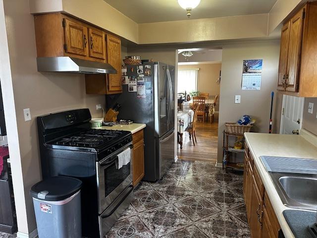 115 N Lavergne Ave, Northlake, IL 60164 - kitchen with gas range, under cabinet range hood, brown cabinets, fridge with ice dispenser, and light countertops