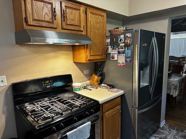 115 N Lavergne Ave, Northlake, IL 60164 - kitchen featuring black gas range oven, under cabinet range hood, brown cabinets, light countertops, and stainless steel fridge