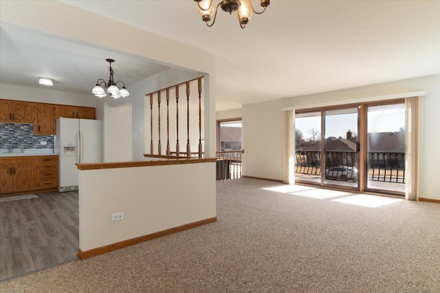 kitchen with white refrigerator with ice dispenser, brown cabinets, pendant lighting, decorative backsplash, and a chandelier