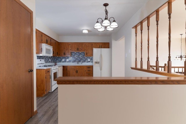 kitchen featuring white appliances, tasteful backsplash, brown cabinetry, decorative light fixtures, and a notable chandelier