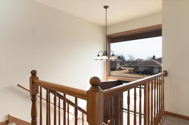 stairway with baseboards and an inviting chandelier