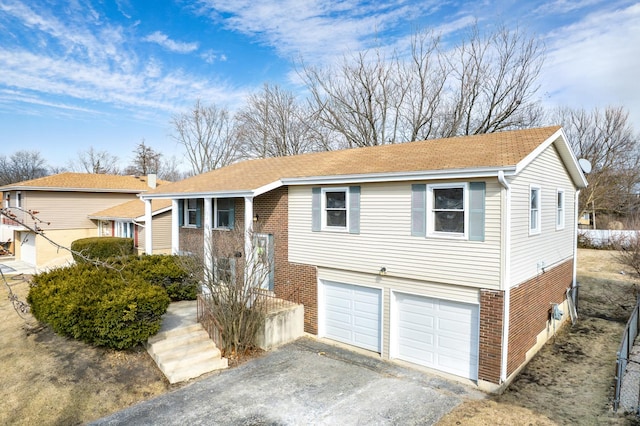 split foyer home with driveway, brick siding, and an attached garage