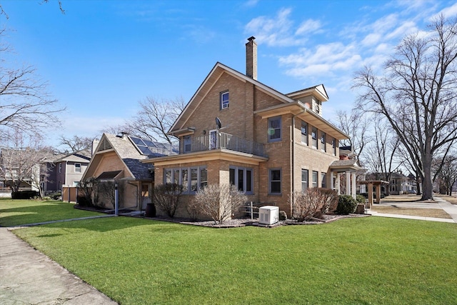 view of property exterior featuring brick siding, central AC unit, a chimney, a yard, and a balcony