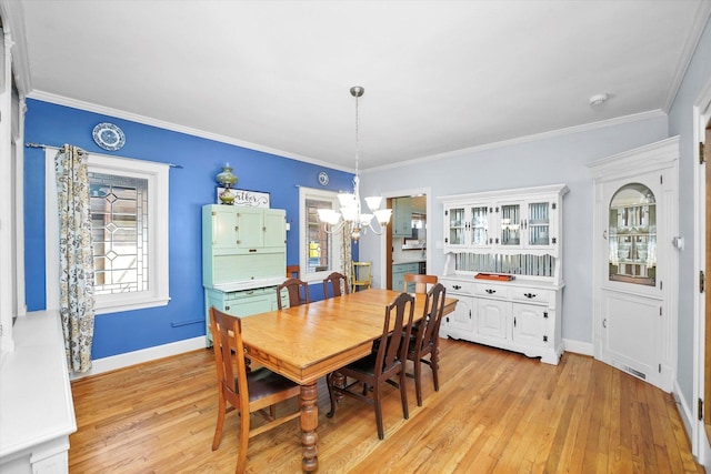 dining area with a chandelier, light wood-style flooring, baseboards, and ornamental molding