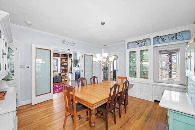 dining room with light wood finished floors, a notable chandelier, and ornamental molding