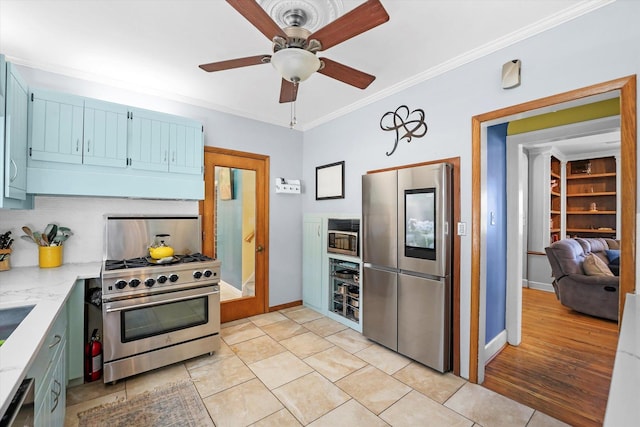 kitchen featuring light tile patterned floors, baseboards, blue cabinetry, ornamental molding, and appliances with stainless steel finishes