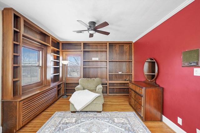 living area with baseboards, ceiling fan, crown molding, and light wood finished floors