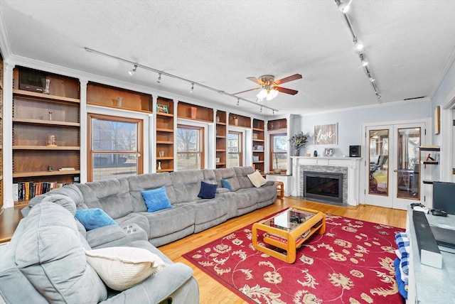 living area with french doors, a textured ceiling, wood finished floors, and a fireplace