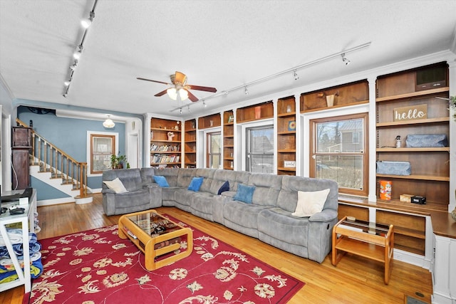 living area featuring hardwood / wood-style floors, stairway, rail lighting, and a textured ceiling