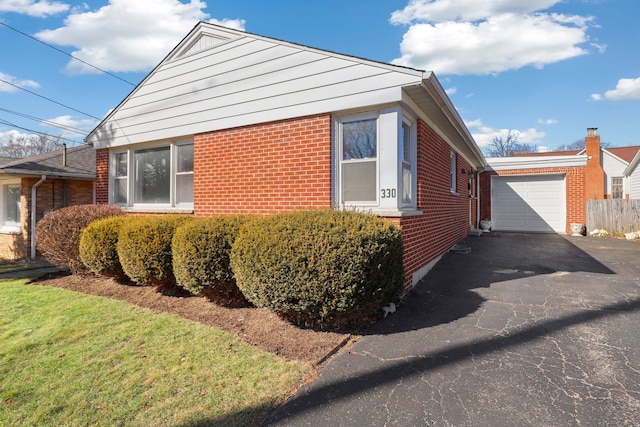 view of property exterior with an outdoor structure, a detached garage, brick siding, and driveway