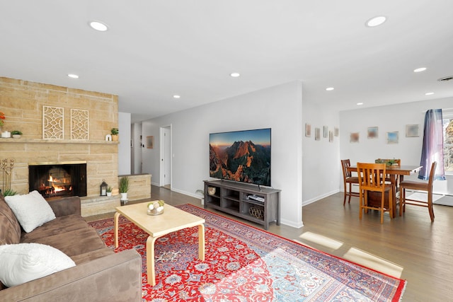 living area with a stone fireplace, recessed lighting, wood finished floors, and baseboards