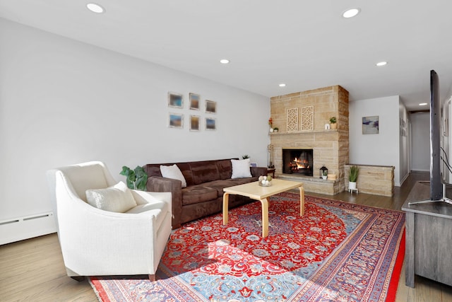 living area featuring recessed lighting, a fireplace, a baseboard heating unit, and wood finished floors