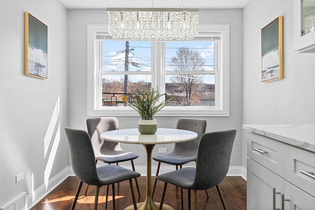 dining area featuring visible vents, baseboards, dark wood-type flooring, and an inviting chandelier