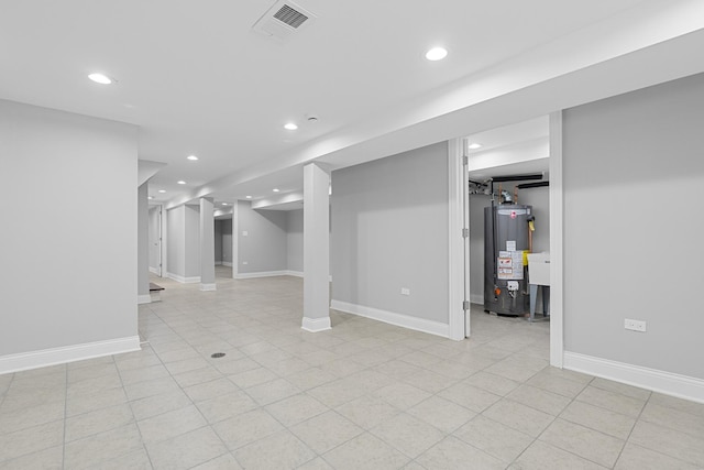 finished basement with water heater, visible vents, recessed lighting, and baseboards