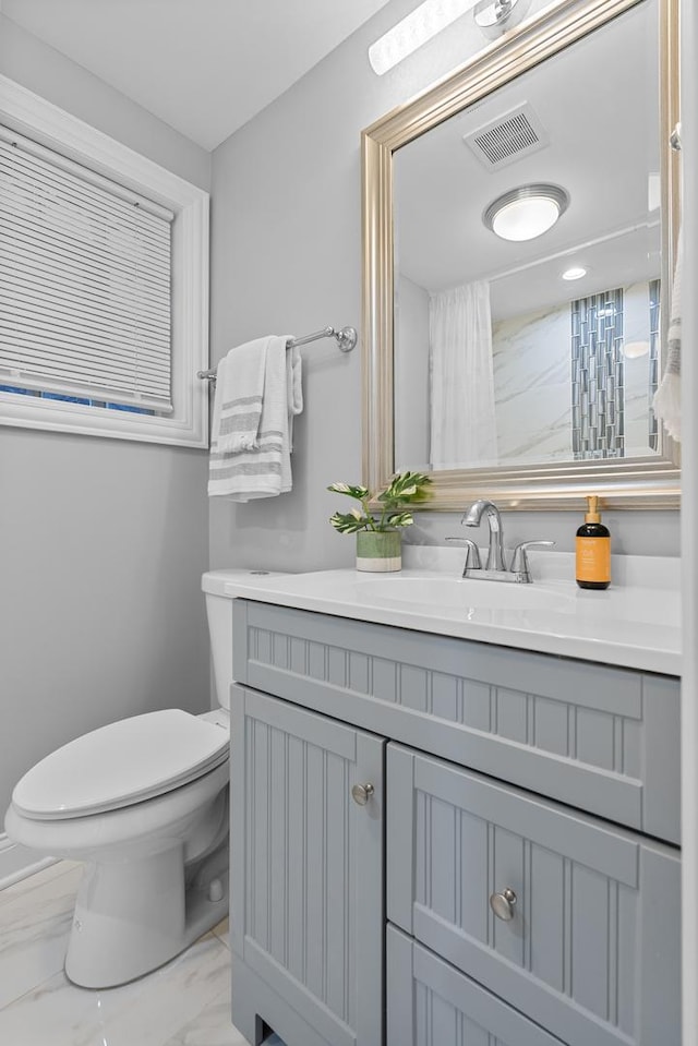 bathroom featuring vanity, toilet, visible vents, and marble finish floor