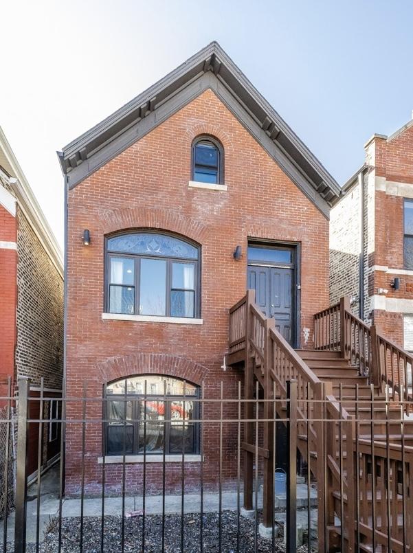 view of front of home featuring stairs, brick siding, and a fenced front yard