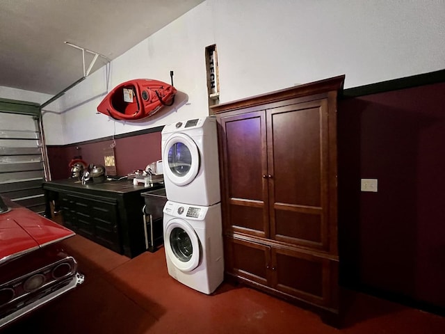 laundry area with laundry area, stacked washer and clothes dryer, and a garage