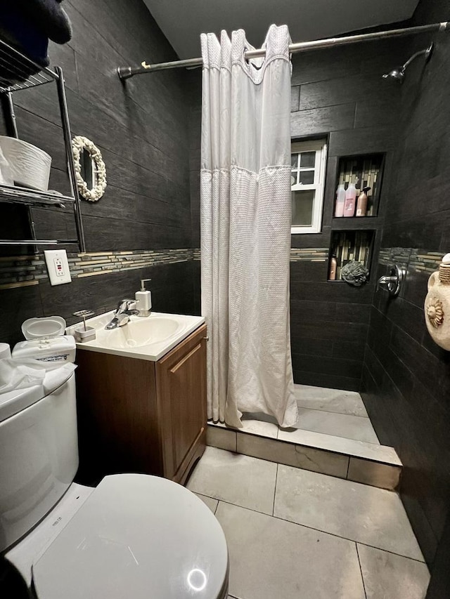 bathroom featuring vanity, toilet, tile patterned flooring, and tiled shower