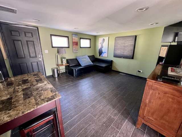 living area with visible vents, baseboards, and dark wood-style floors