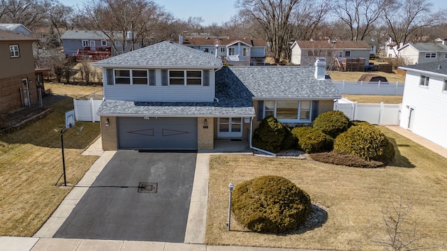 view of front of home with aphalt driveway, fence, a residential view, an attached garage, and brick siding