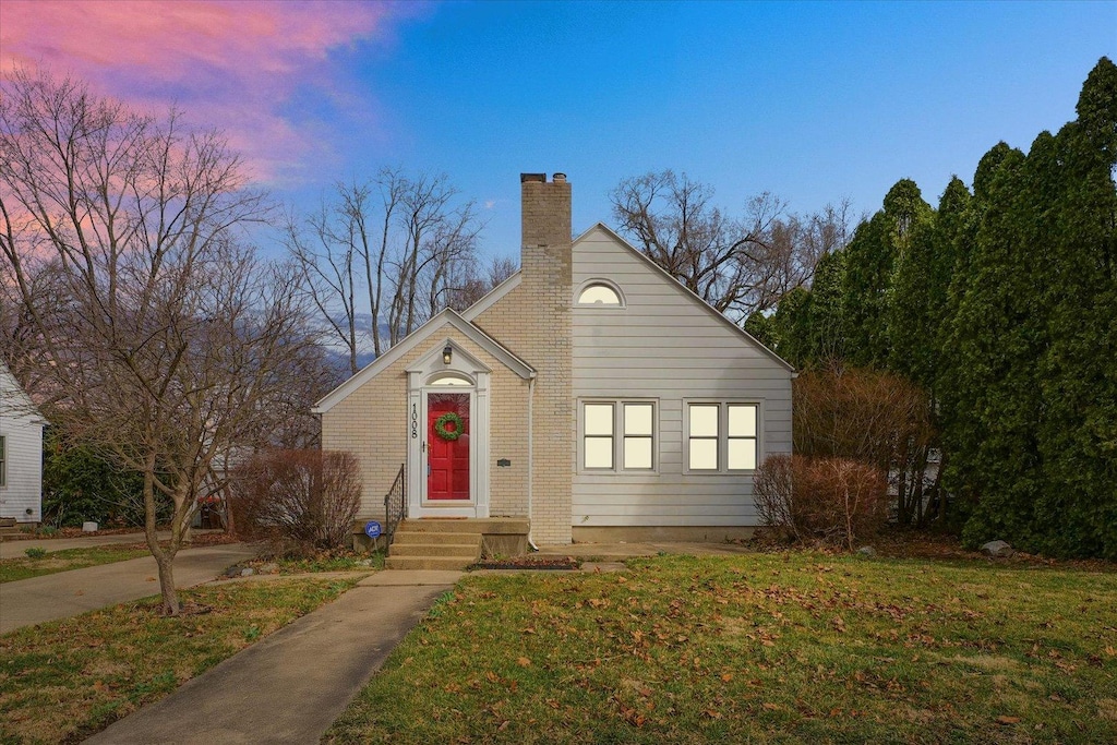 bungalow-style house with a lawn and a chimney