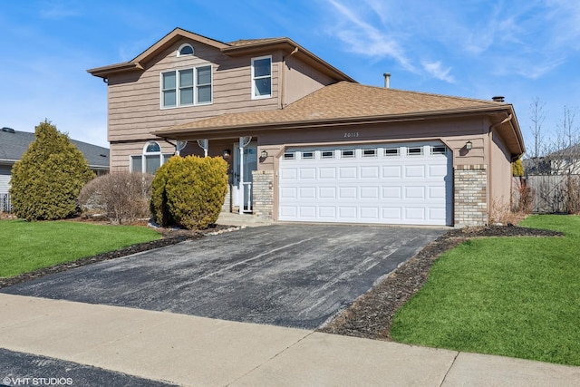 traditional home with a garage, aphalt driveway, a front yard, and brick siding