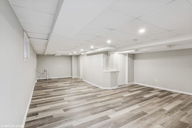 finished below grade area featuring a paneled ceiling, light wood finished floors, baseboards, and recessed lighting