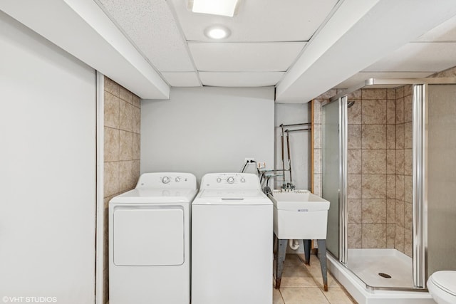 laundry room with laundry area, light tile patterned floors, separate washer and dryer, and tile walls