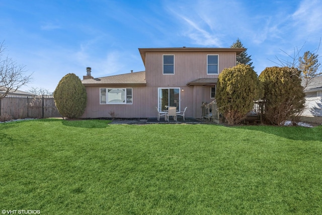 rear view of property featuring a chimney, fence, and a lawn