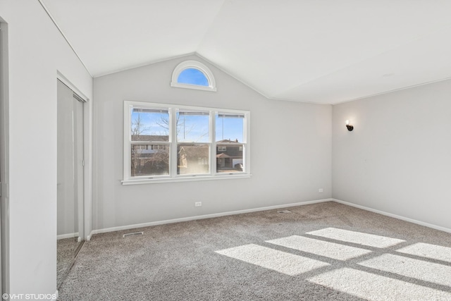 unfurnished bedroom with carpet floors, visible vents, baseboards, vaulted ceiling, and a closet