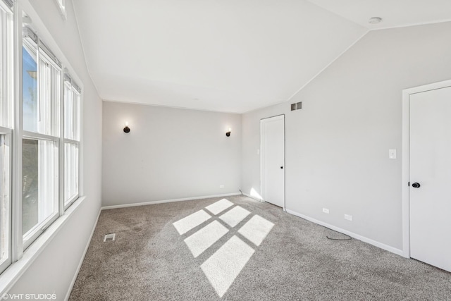 unfurnished room with lofted ceiling, visible vents, baseboards, and carpet flooring