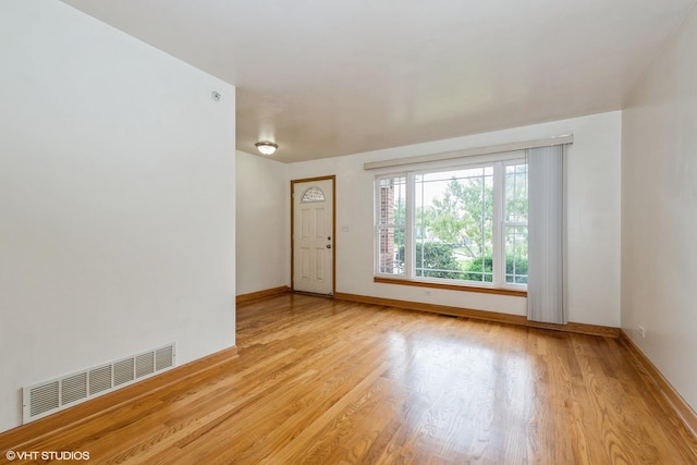 spare room with baseboards, visible vents, and wood finished floors