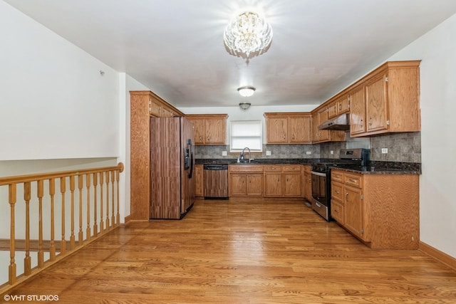 kitchen with dishwasher, stainless steel range with gas stovetop, under cabinet range hood, refrigerator with ice dispenser, and a sink