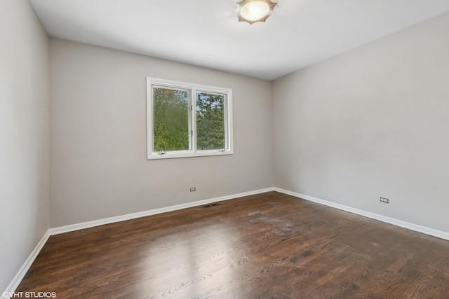 empty room featuring dark wood-style floors and baseboards