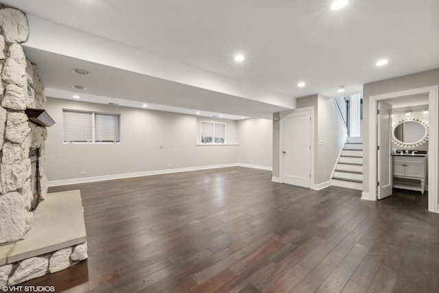 finished basement with baseboards, dark wood-style floors, stairway, a fireplace, and recessed lighting